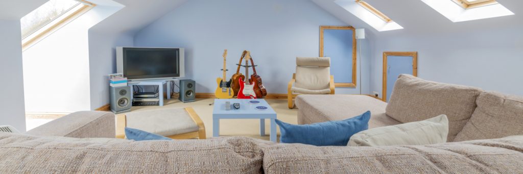 a loft with sofa, TV and guitars