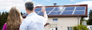Couple stood infront of a house looking at solar panels on roof